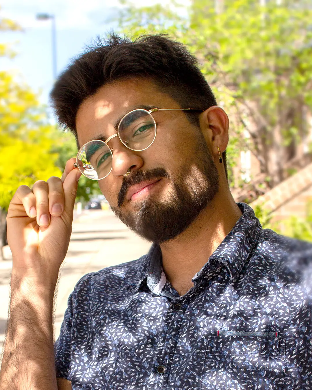 Portrait of Joseph from the Studio J Lorne team adjusting his glasses outdoors