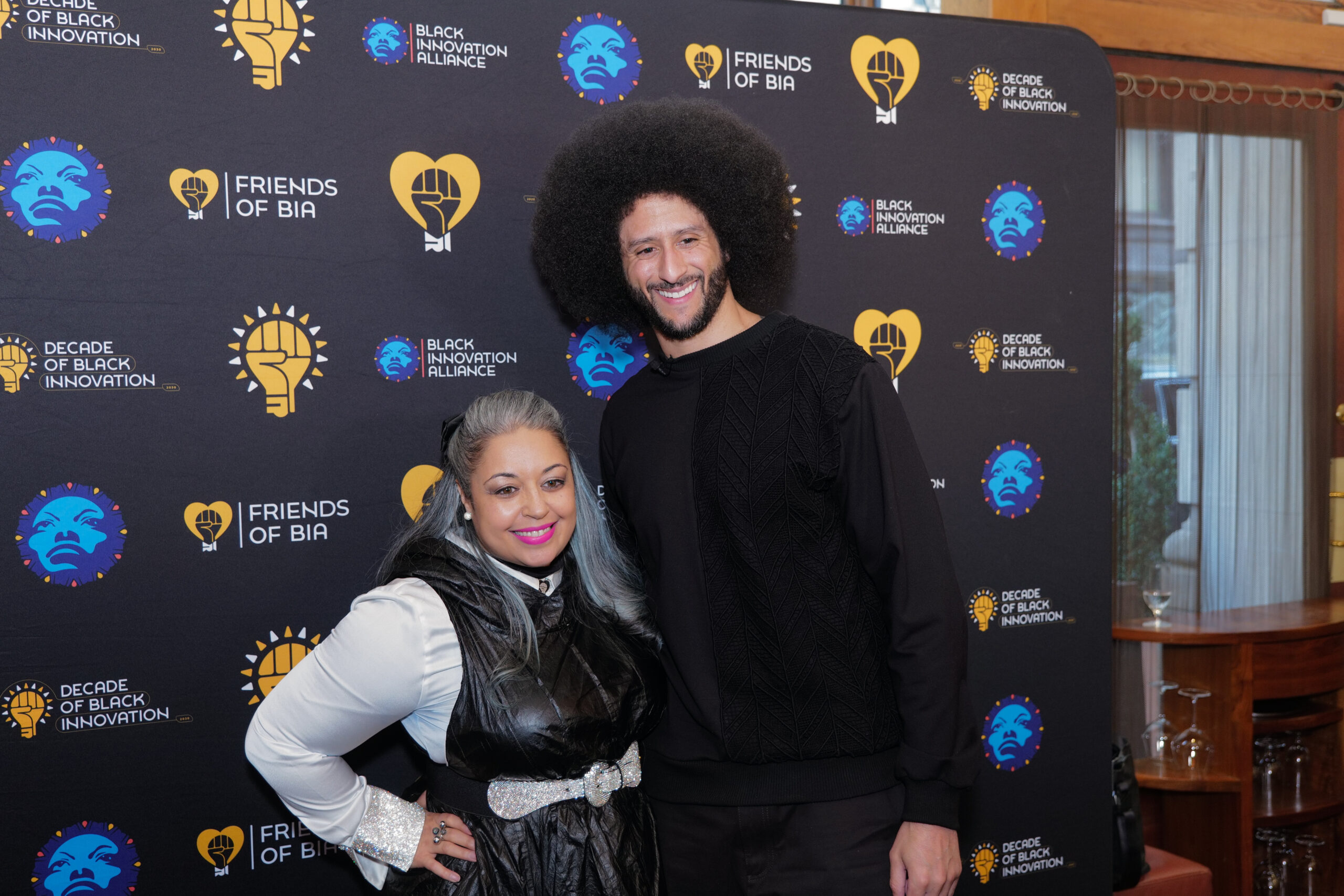 Colin Kaepernick and a guest at the Friends of BIA step and repeat during the DoBI Salon
