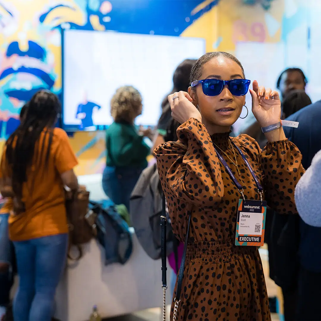 Immersive event branding with an attendee trying on branded sunglasses at the Web Summit booth
